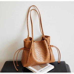 Detail of brown ostrich texture leather shoulder bag with side drawstring and long straps
