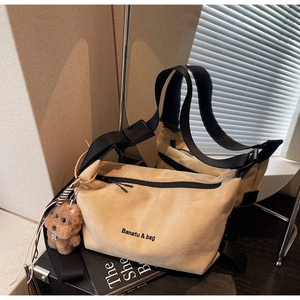 Detail of khaki canvas hobo bag with wide nylon strap and cute plush puppy charm
