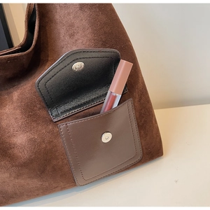 Detail of deep brown suede tote bag featuring a front pocket and magnetic closure