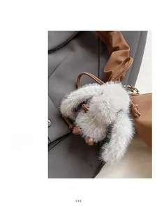 Detail of grey faux fur bunny bag charm with gold clasp on a luxury handbag