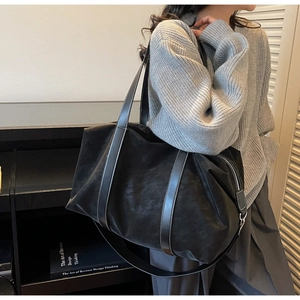 Detail of black large tote bag featuring leather handles and white contrast stitching