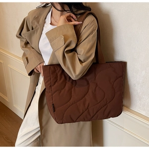 Macro detail of dark brown quilted tote bag with wave stitching and nylon texture