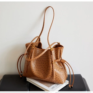 Close-up of brown ostrich texture tote bag featuring side drawstring and gold ring