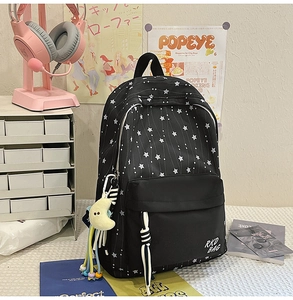 Détail du sac à dos noir en nylon avec imprimés étoiles et breloque peluche lune jaune
