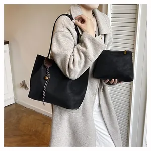 Minimalist black leather tote bag set with matching inner pouch and brown fur pompom detail