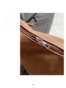 Detailed macro view of the smooth silver zipper on brown lychee texture leather bag