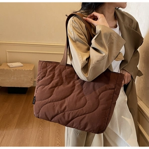 Detail of coffee wave-quilted tote bag showing the textured down padding and brand tag