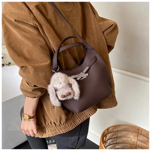 Detail of dark brown leather bucket bag with metal buckle and plush bunny charm