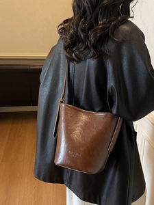 Brown vintage faux leather bucket bag with glossy oil-wax finish shown on a model