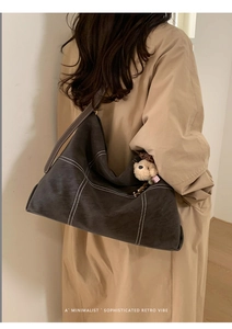 Detail of vintage matte leather tote bag with contrast stitching and bear charm