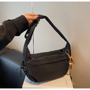 Detail of black nylon hobo bag showing adjustable strap and ethnic style beaded pendant