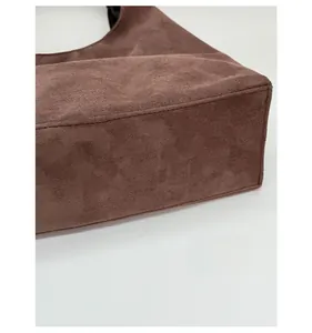 Detail of the widened bottom base of a large brown suede tote bag for extra storage