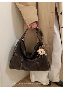 Detail of dark brown matte tote with contrast stitching and cream dog plush charm
