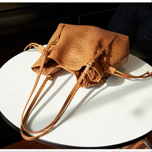 Detailed close-up of brown ostrich texture tote bag with vintage gold metal buckle