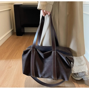 Close-up of a large dark brown tote bag with contrast stitching and leather handles