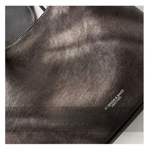 Close-up of pebble grain leather with contrast white stitching on a retro tote bag