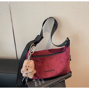 Detailed close-up of burgundy suede hobo bag with Banatu branding and plush bear charm