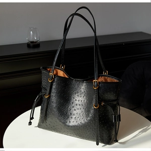 Detail of black ostrich embossed tote bag featuring vintage gold hardware and drawstrings
