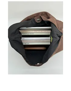 Spacious interior of brown suede tote bag with magnetic clasp and books for capacity view
