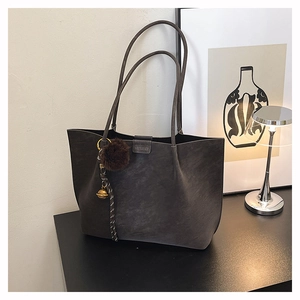 Macro detail of charcoal grey faux suede tote bag with handle flap and brand embossing