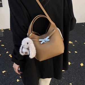 Close-up of brown bucket bag with lychee texture, silver buckle, and rabbit plush charm