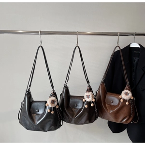 Detailed view of leather tote bags in black, dark brown, and coffee with plush charms
