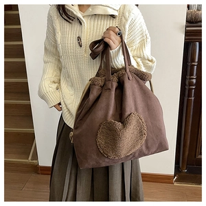 Detail of vintage suede tote bag featuring a plush brown heart and drawstring closure
