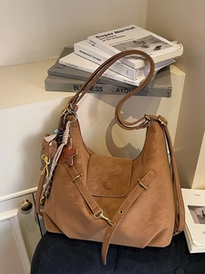 Vintage large brown hobo bag with teddy bear pendant on minimalist book background