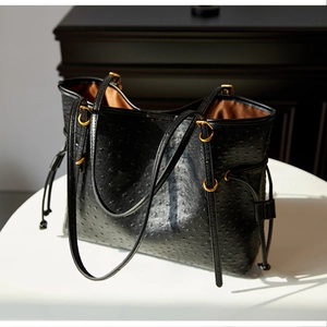 Detail of ostrich texture tote bag showing gold ring buckle and smooth satin lining interior