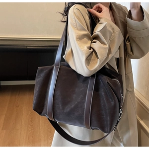Detail shot of a dark brown suede tote bag featuring a leather strap and zip closure