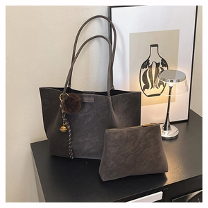 Detail of dark gray matte tote bag with small zipper pouch and brown pompom charm