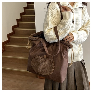 Detail of vintage brown suede tote bag with plush shearling trim and apple patch