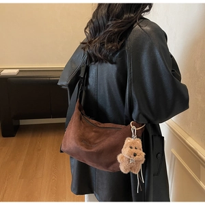 Brown suede crescent bag with zipper closure and cute puppy charm on wide black strap