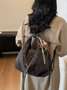 Vintage large brown hobo shoulder bag with cute bear charm worn by a model in beige coat