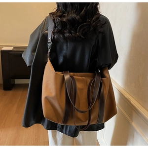 Detail of a large brown tote bag with premium leather straps and contrast stitching