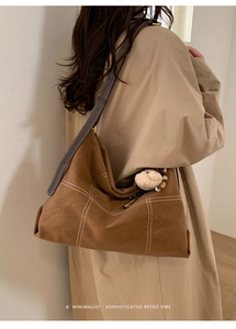 Detail of retro brown suede tote bag with white contrast stitching and cute lamb charm