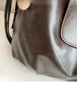 Detail of dark brown faux leather tote bag with a soft yellow plush charm pendant