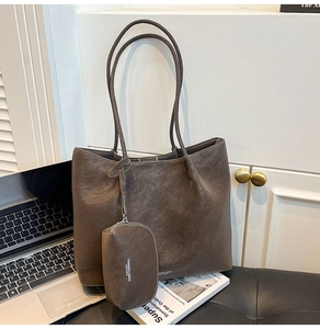 Detail of dark brown matte leather tote with white contrast stitching and a small pouch