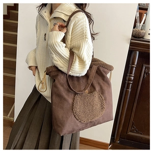 Detail of dark brown faux suede tote bag featuring a plush apple patch and fleece trim edges
