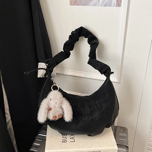 Detail of black moon bag with pleated handle and cute white plush bunny charm