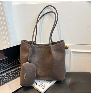 Detail of dark brown matte tote bag set with white stitching and hanging accessory