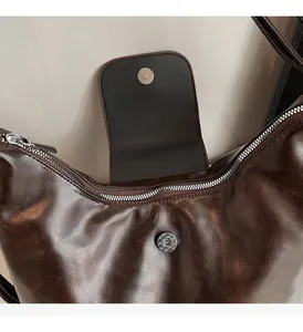 Detail of dark brown oil wax leather bag featuring silver metal zipper and magnetic buckle