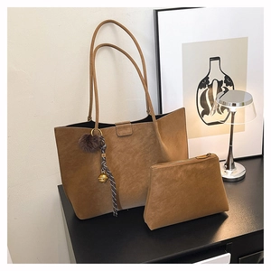 Detail view of tan suede tote bag with brand logo embossing and matching mini pouch