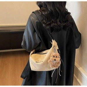 Detail of beige corduroy half-moon crossbody bag with black strap and plush puppy charm