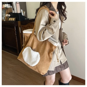 Close-up of large suede tote bag with white fleece heart patch and drawstring detail