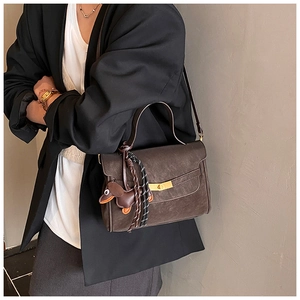 Detail of vintage coffee brown crossbody bag with dachshund pendant and metal twist lock