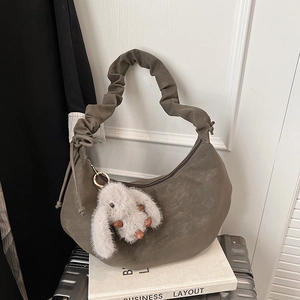 Detail of dark olive hobo bag featuring ruched cloud strap and cute rabbit pendant