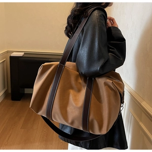 Detail view of large brown travel bag showing white contrast stitching and soft texture