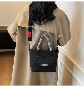 Vue arrière du sac cabas en nylon noir avec poignées tressées porté sur un trench-coat