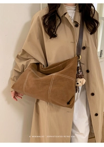 Detail of vintage brown tote bag with contrast stitching and plush bear charm